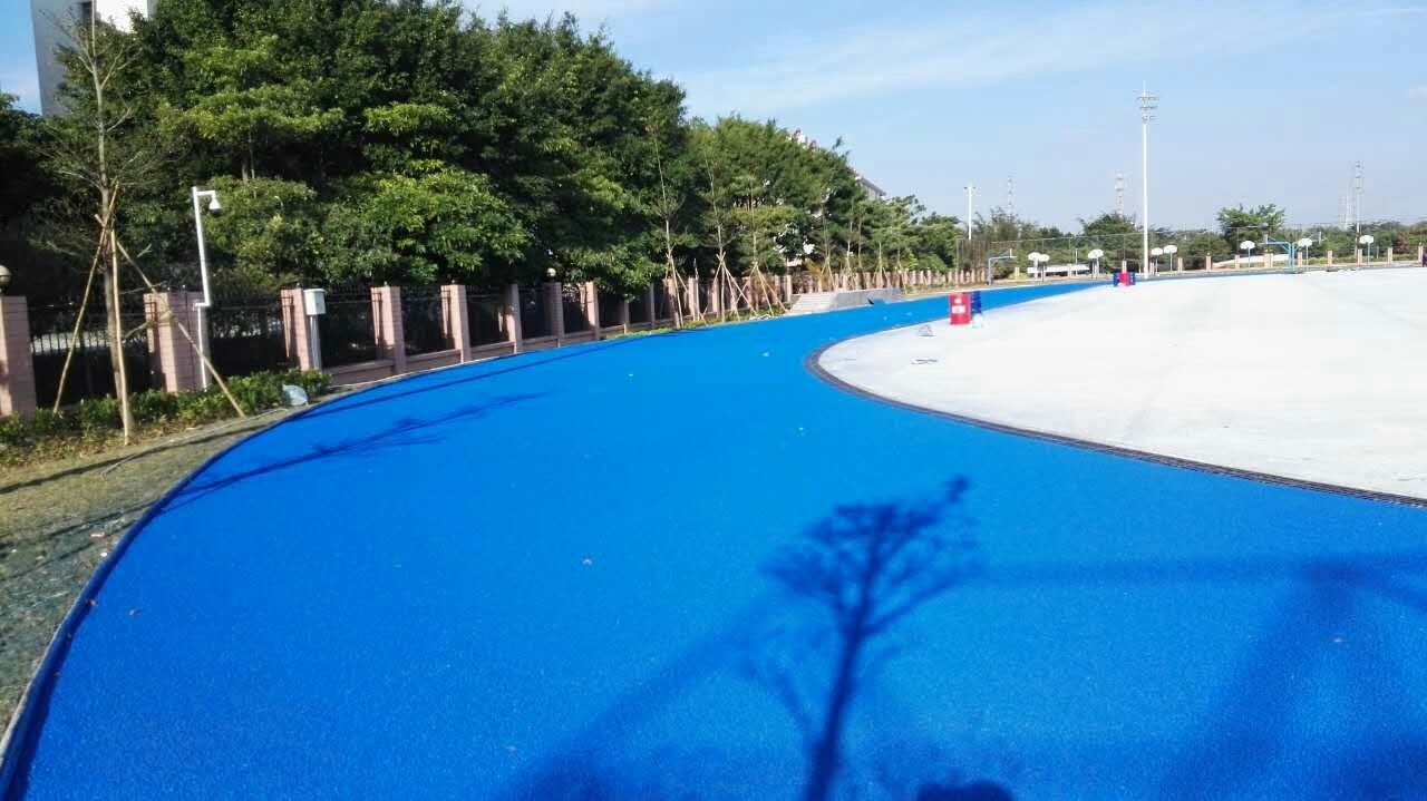 珠海金洲小学运动场透气型跑道环保颗粒摊铺 蓝色跑道面层喷面。
